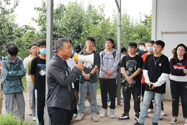 杨勇研究员为学生介绍柿种质资源圃情况.png